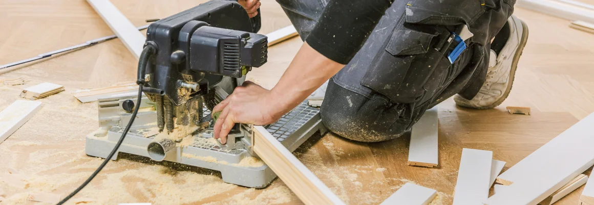 Person sägt Sockelleiste mit Säge.